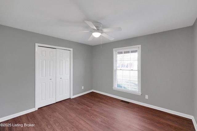 unfurnished bedroom with ceiling fan, dark hardwood / wood-style flooring, and a closet