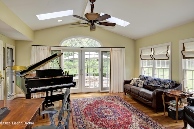 living area featuring hardwood / wood-style flooring, vaulted ceiling with skylight, and french doors