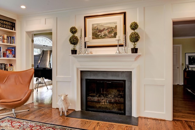 living area featuring hardwood / wood-style floors, crown molding, and built in shelves