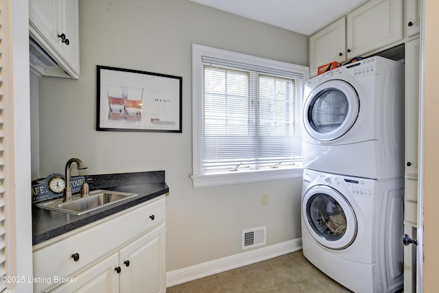 washroom featuring cabinets, light tile patterned flooring, stacked washer and clothes dryer, and sink