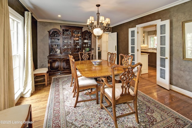 dining area featuring a notable chandelier, light hardwood / wood-style flooring, ornamental molding, and sink