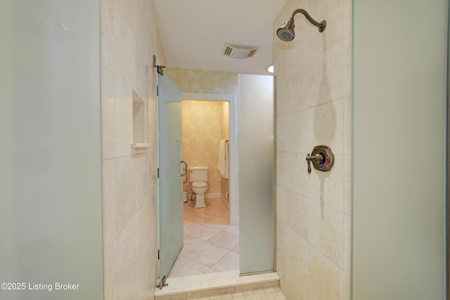 bathroom featuring toilet, tile patterned flooring, and a shower with door