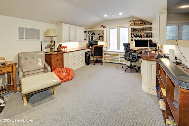 office space featuring light colored carpet, lofted ceiling, and built in desk