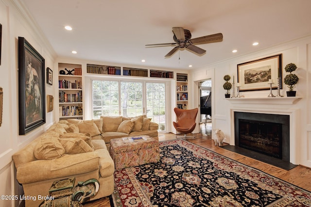 living room with ceiling fan, ornamental molding, hardwood / wood-style floors, and built in features