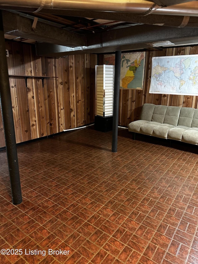 below grade area featuring wooden walls and brick floor