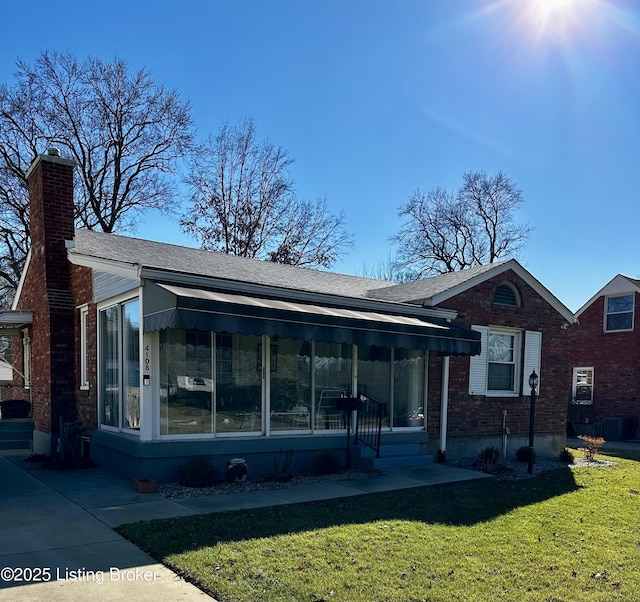 view of front of house with brick siding, a chimney, and a front lawn