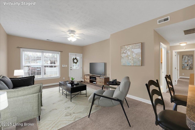 carpeted living room with ceiling fan and a textured ceiling