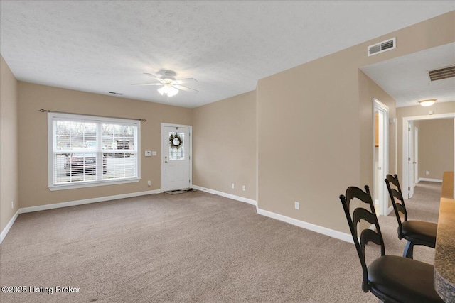 carpeted foyer entrance with ceiling fan and a textured ceiling