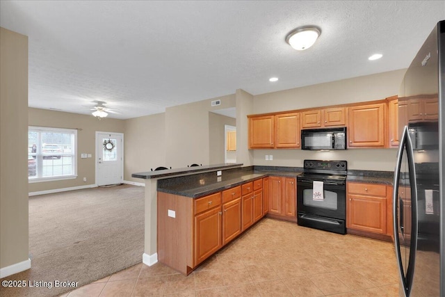 kitchen with light colored carpet, a textured ceiling, kitchen peninsula, ceiling fan, and black appliances