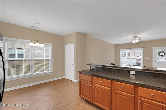 kitchen with pendant lighting, light tile patterned floors, ceiling fan with notable chandelier, and a textured ceiling