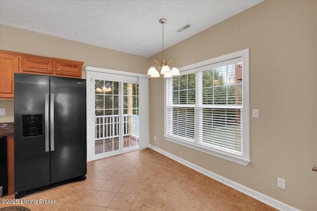 kitchen featuring hanging light fixtures, light tile patterned floors, stainless steel fridge, and a chandelier