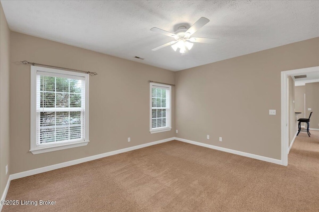 empty room with ceiling fan, light carpet, and a textured ceiling