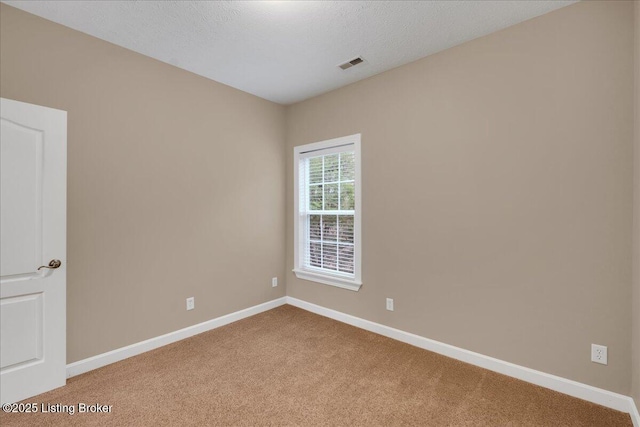 carpeted empty room featuring a textured ceiling