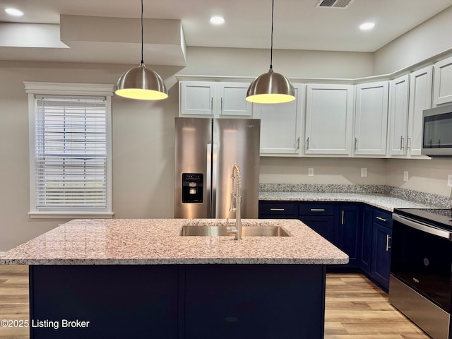 kitchen featuring a kitchen island with sink, white cabinetry, pendant lighting, and stainless steel appliances