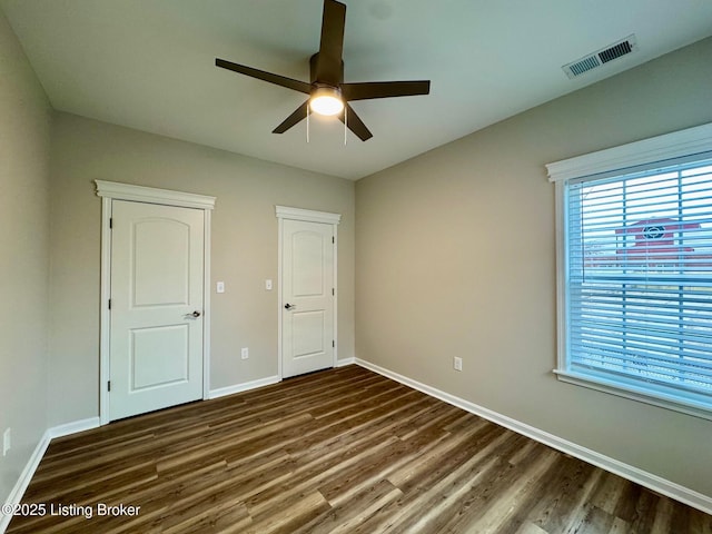 unfurnished bedroom with dark wood-type flooring, ceiling fan, and multiple windows