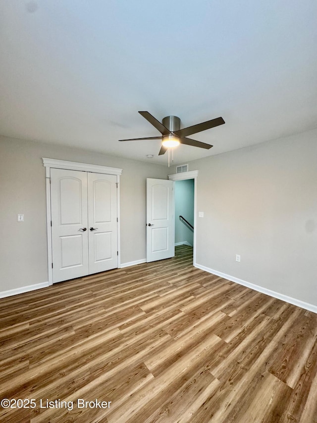 unfurnished bedroom with ceiling fan, a closet, and light wood-type flooring