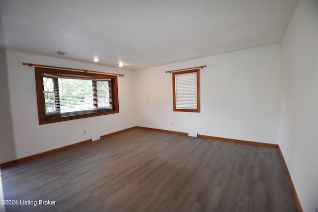 spare room featuring dark wood-type flooring and a textured ceiling