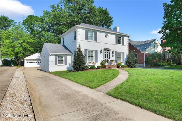 colonial-style house featuring an outbuilding, a garage, and a front yard