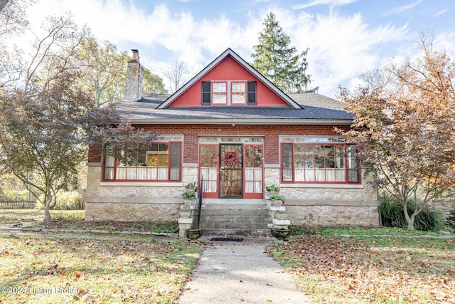 view of front of property featuring stone siding, a shingled roof, a chimney, and brick siding