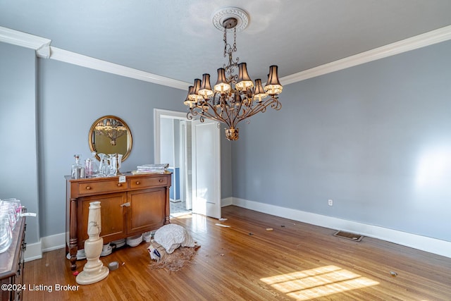 dining area with hardwood / wood-style flooring, ornamental molding, and a chandelier