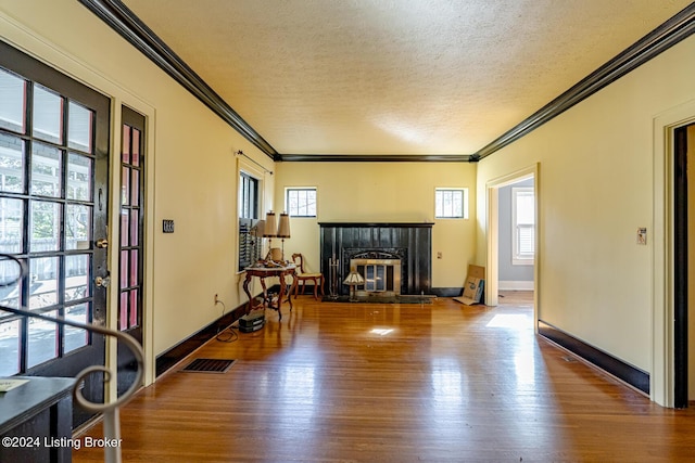 living room featuring a textured ceiling, visible vents, wood finished floors, and ornamental molding