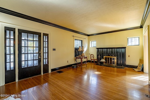 unfurnished living room featuring visible vents, a glass covered fireplace, crown molding, and wood finished floors