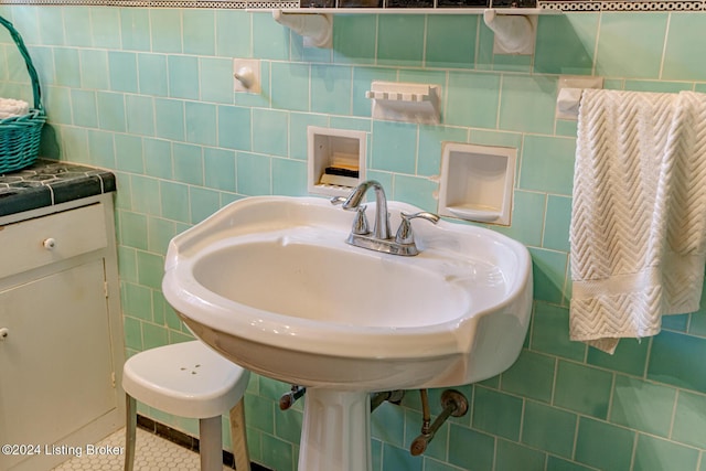 bathroom featuring tile patterned flooring, a sink, and tile walls