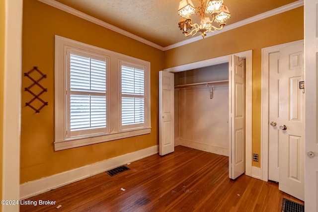 unfurnished bedroom featuring crown molding, wood-type flooring, a textured ceiling, a closet, and a notable chandelier