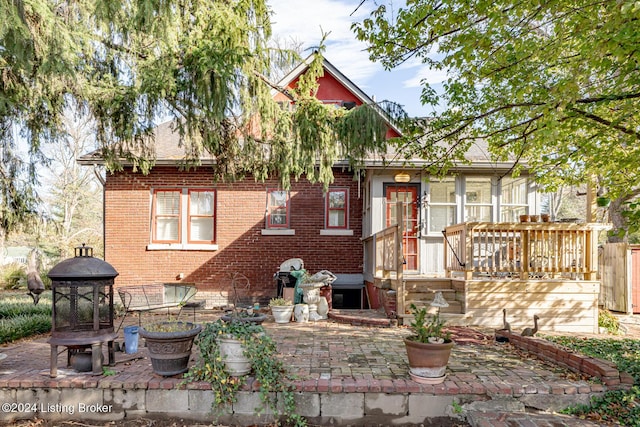 back of house with a deck, a patio, and brick siding