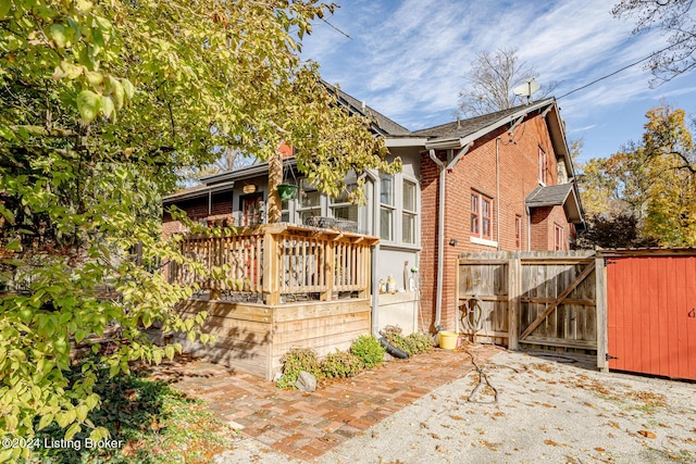 exterior space featuring a gate, brick siding, fence, and a wooden deck