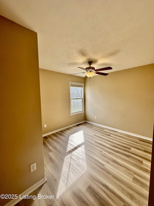 unfurnished room with ceiling fan, a textured ceiling, and light wood-type flooring