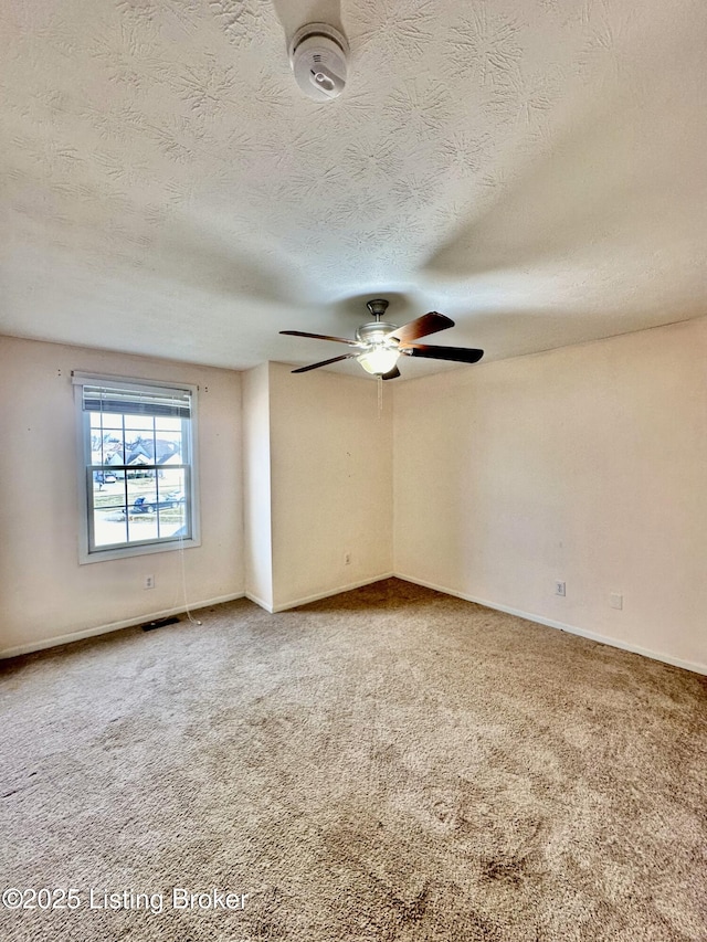 carpeted empty room with ceiling fan and a textured ceiling