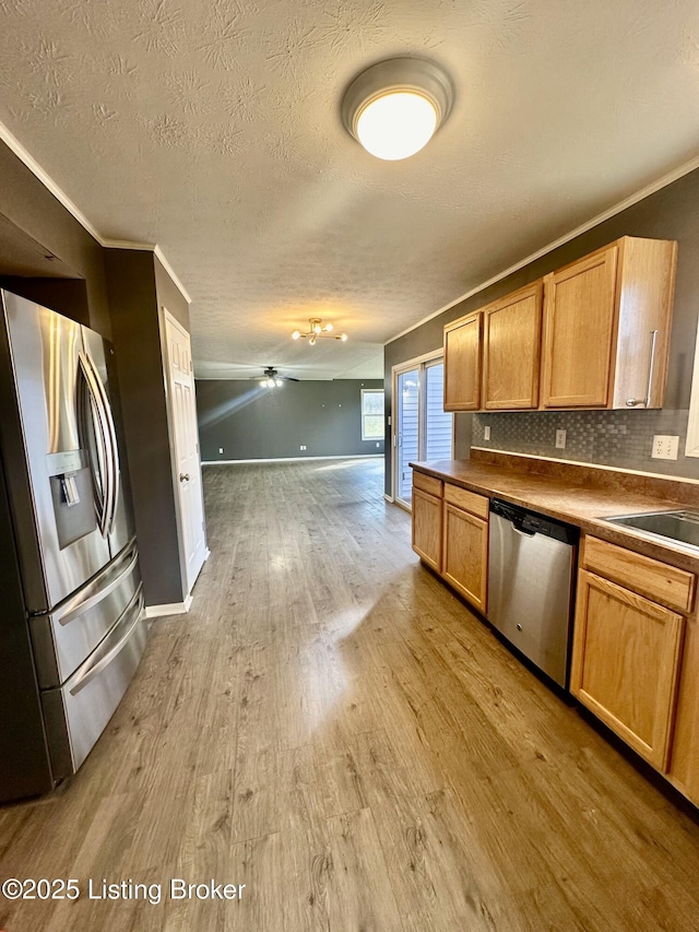 kitchen featuring ornamental molding, appliances with stainless steel finishes, sink, and light wood-type flooring