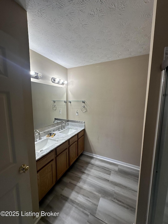 bathroom with vanity, wood-type flooring, and a textured ceiling