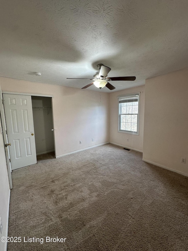 spare room featuring a textured ceiling, ceiling fan, and carpet flooring