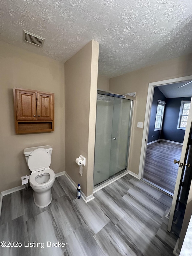 bathroom featuring toilet, an enclosed shower, hardwood / wood-style floors, and a textured ceiling