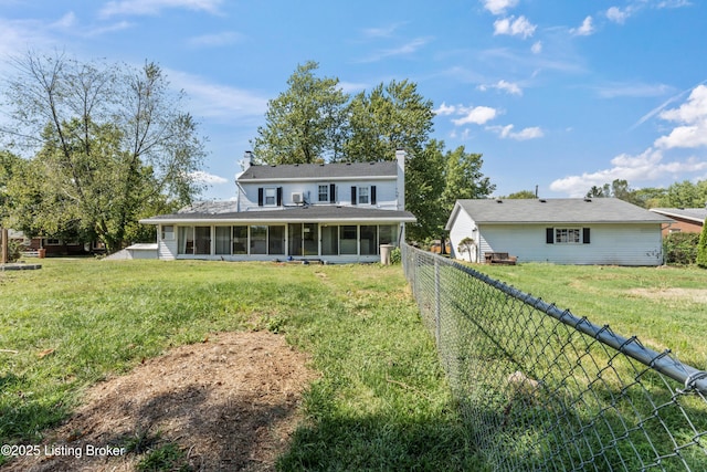 rear view of property with a sunroom and a lawn