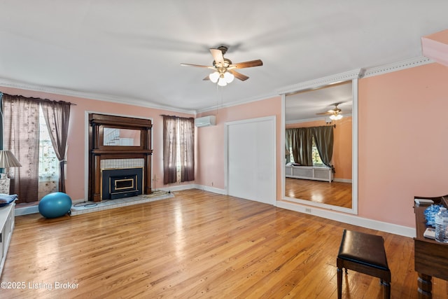 living room featuring a wall mounted air conditioner, a wealth of natural light, a tile fireplace, and light wood-type flooring