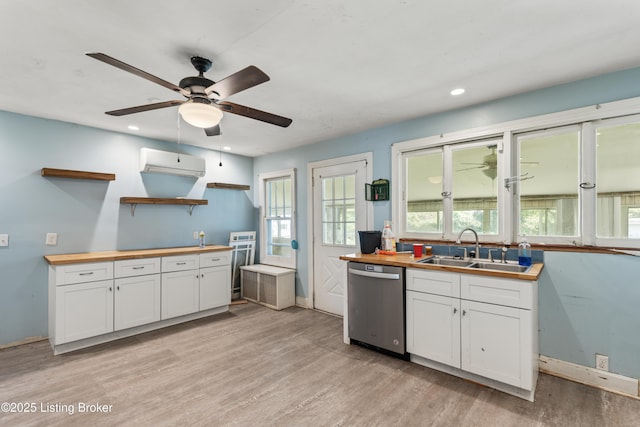 kitchen with butcher block countertops, sink, white cabinetry, a wall mounted air conditioner, and stainless steel dishwasher