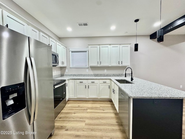 kitchen featuring pendant lighting, sink, white cabinets, light stone counters, and stainless steel appliances