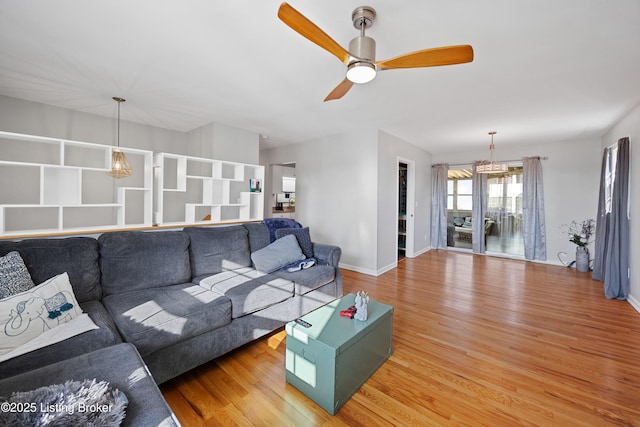 living room with wood-type flooring and ceiling fan with notable chandelier