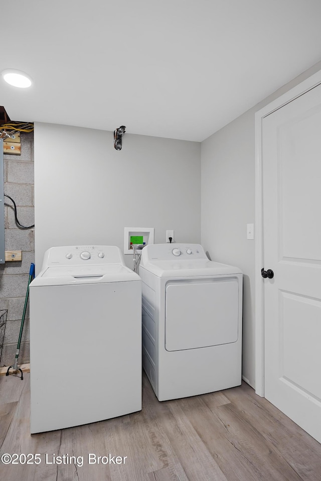 clothes washing area with washing machine and clothes dryer and light hardwood / wood-style floors