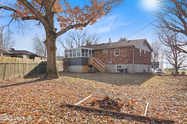 rear view of property with central AC unit and a sunroom