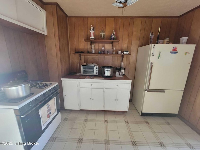 kitchen featuring white cabinetry, white appliances, and wood walls