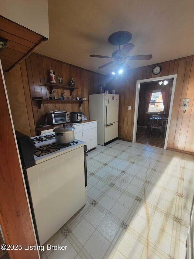 kitchen with white refrigerator, wooden walls, and gas range oven