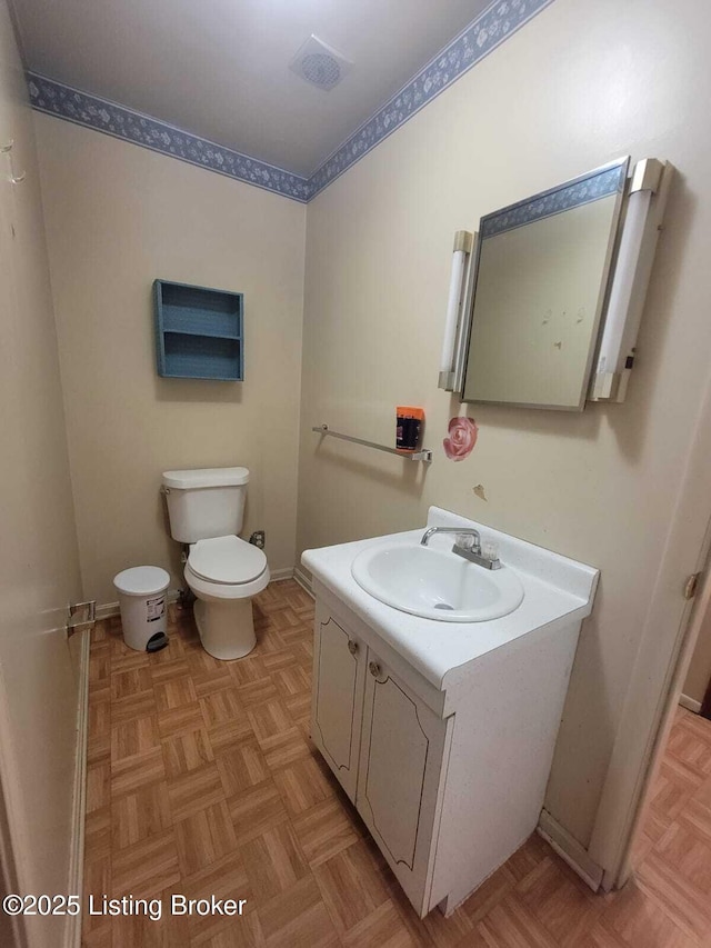 bathroom featuring parquet floors, vanity, and toilet