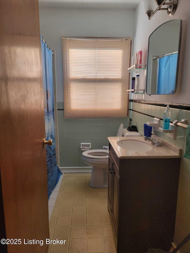 bathroom with vanity, toilet, and tile walls