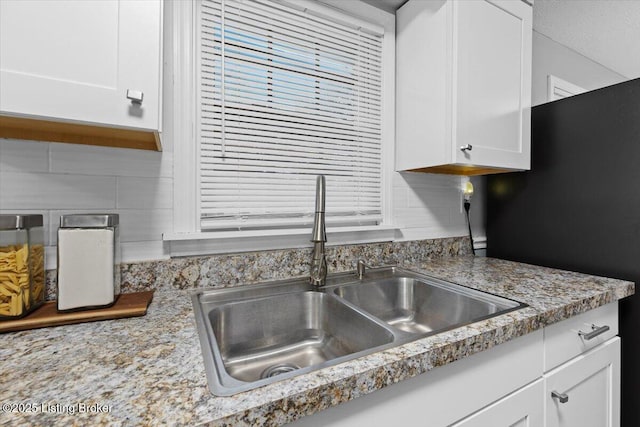 kitchen with black refrigerator, sink, and white cabinets