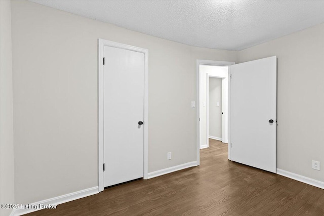 unfurnished bedroom featuring dark wood-type flooring and a textured ceiling