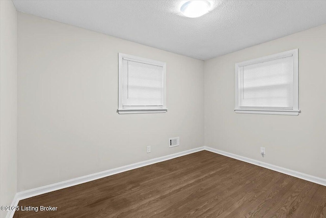 unfurnished room featuring dark wood-type flooring and a textured ceiling